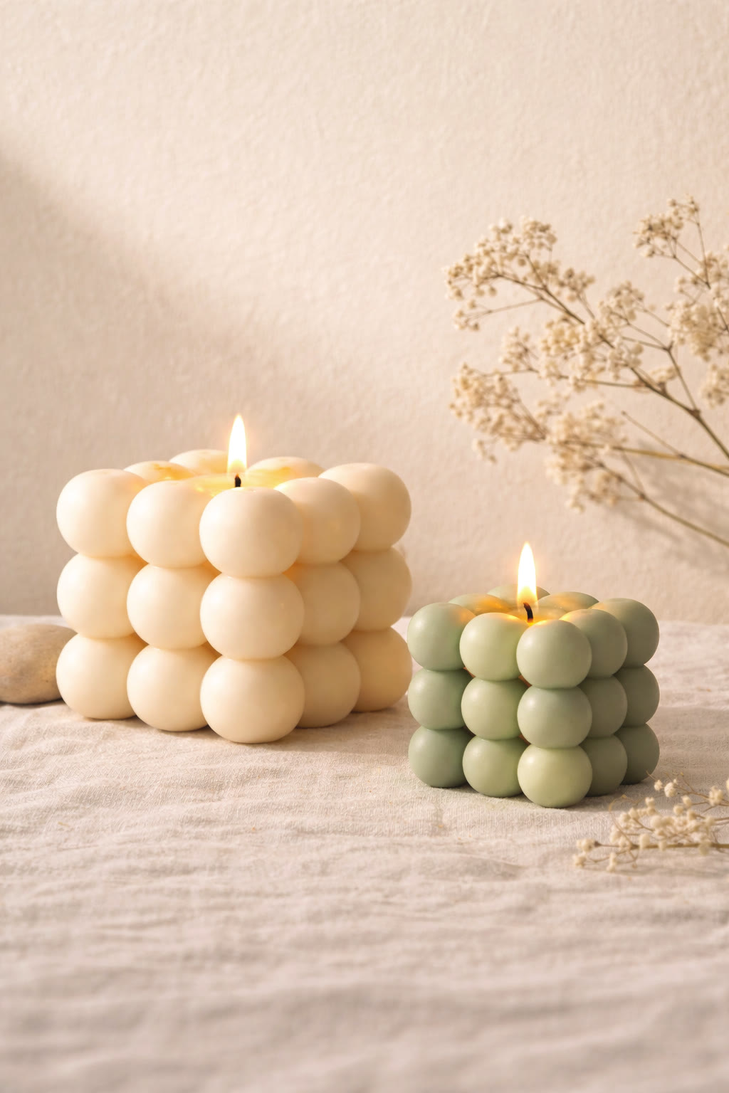 A lit Porcelain Bubble candle beside a lit Sage mini Bubble on soft linen